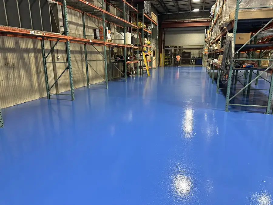 Warehouse floor after solid blue epoxy coating, racking aisles